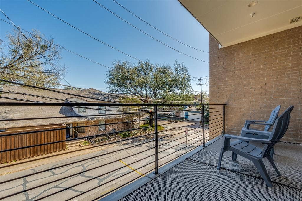 805 Pavillion Street, #103, Dallas, TX 75204 Balcony with black metal horizontal railing and overhead lighting, featuring a brick exterior wall and textured outdoor flooring