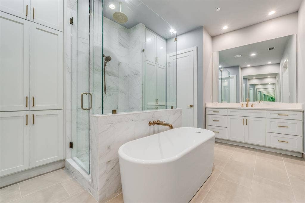 805 Pavillion Street, #103, Dallas, TX 75204 Freestanding soaking tub, glass-enclosed shower with a rain showerhead, double vanity with an integrated mirror, and extensive built-in cabinetry
