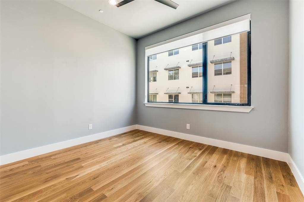 805 Pavillion Street, #103, Dallas, TX 75204 Light-filled room featuring wood-finish flooring, a contemporary ceiling fan, and a wide window with white trim