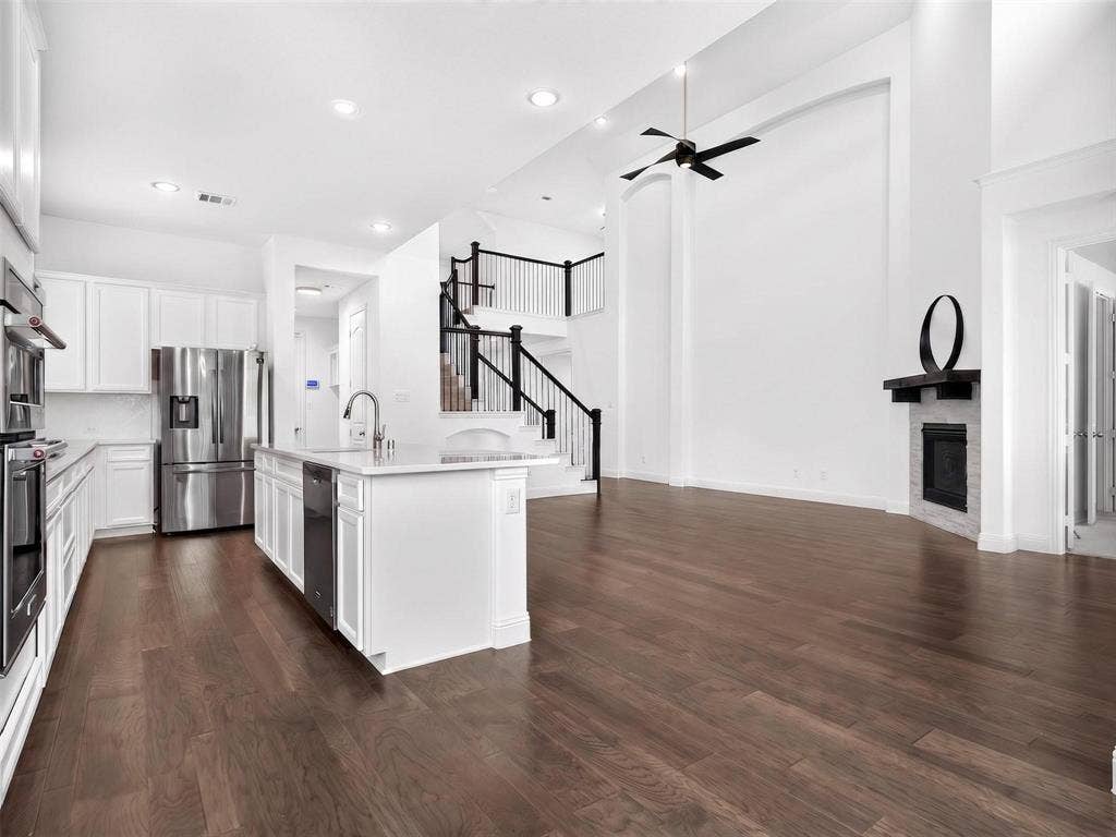 6504 Dynamite Drive, McKinney, TX 75070 Expansive living area with wood-finish flooring, a fireplace, and a high ceiling with an attached fan