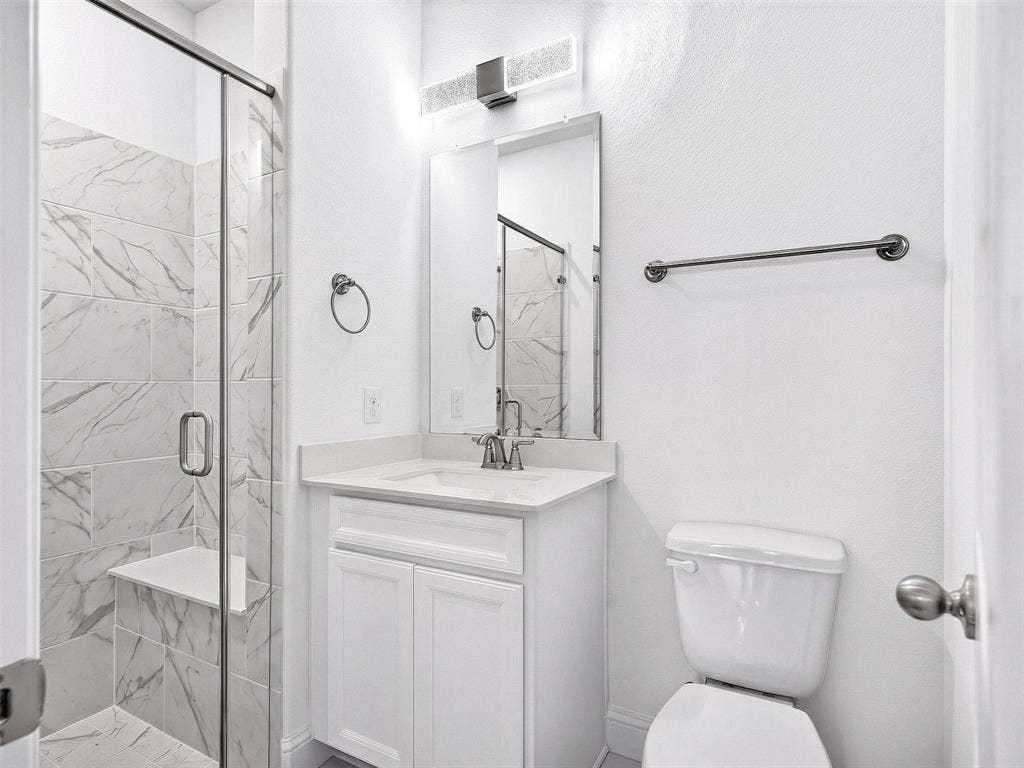 6504 Dynamite Drive, McKinney, TX 75070 Glass-enclosed shower with a built-in bench and marble-look tile