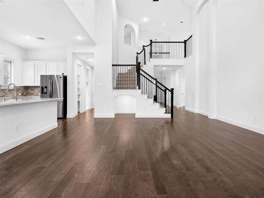 6504 Dynamite Drive, McKinney, TX 75070 Soaring ceilings, rich wood-finish flooring, and a grand staircase with dark balusters
