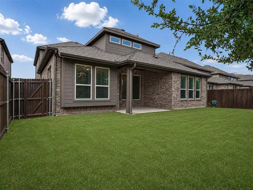 6504 Dynamite Drive, McKinney, TX 75070 Expansive green lawn, covered patio, brick and siding exterior, multi-pane windows, and privacy fencing