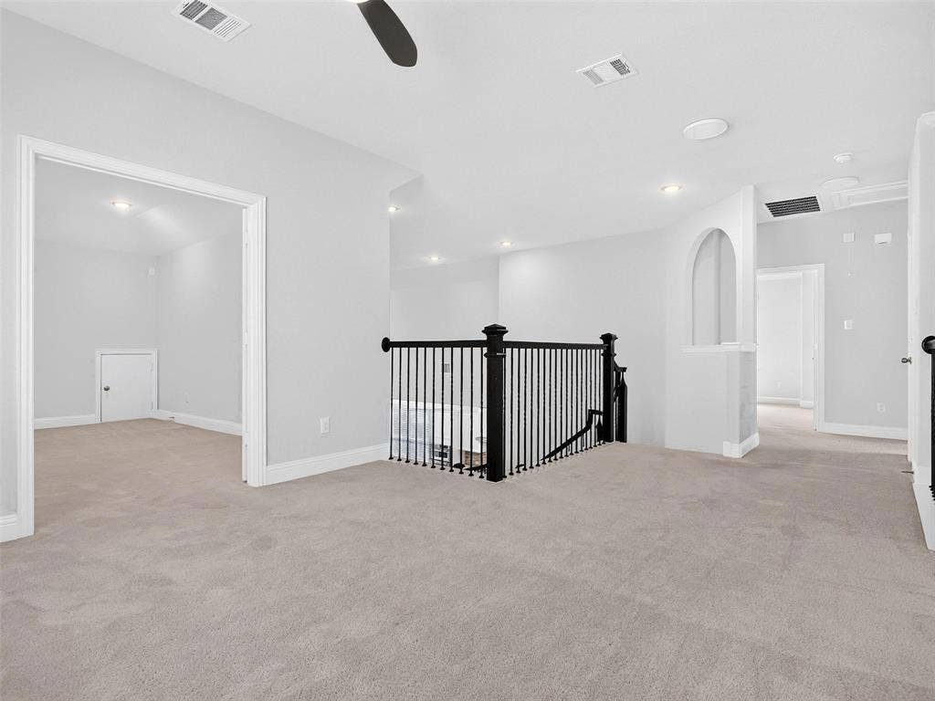 6504 Dynamite Drive, McKinney, TX 75070 Open concept upper level featuring plush carpeting, a black wrought iron staircase railing, recessed lighting, and an arched hallway opening