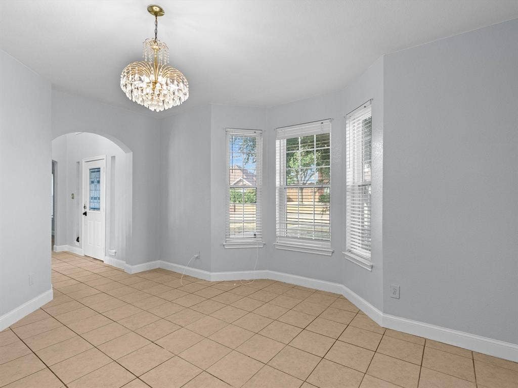 7302 San Carlos Drive, Rowlett, TX 75089 Chandelier lighting, arched doorway, bay windows with horizontal blinds, and tile flooring