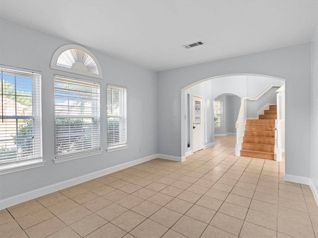7302 San Carlos Drive, Rowlett, TX 75089 Tile flooring, multiple windows, arched window feature, arched doorway, and wood-finish staircase with white risers