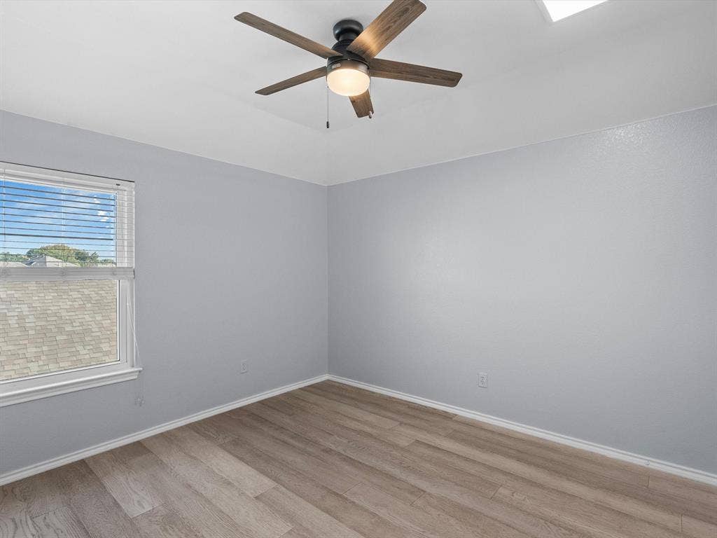 7302 San Carlos Drive, Rowlett, TX 75089 Wood-finish flooring, white trim, and a ceiling fan with integrated lighting