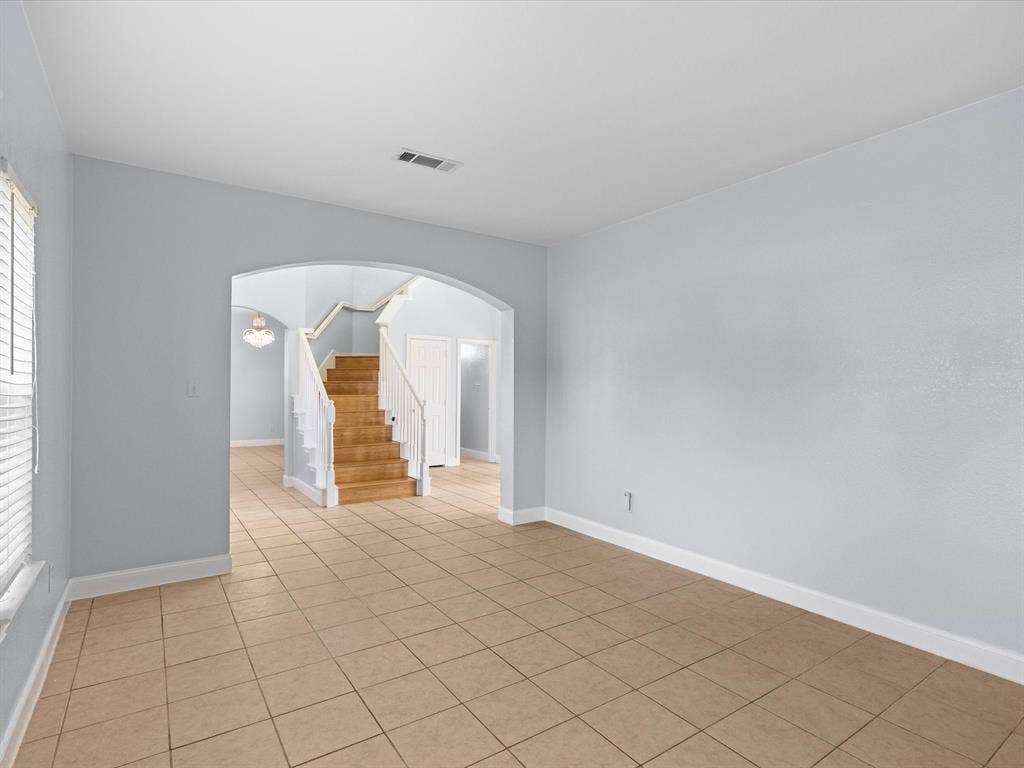 7302 San Carlos Drive, Rowlett, TX 75089 Tile flooring extending through an arched doorway to a wooden staircase with white risers and railings