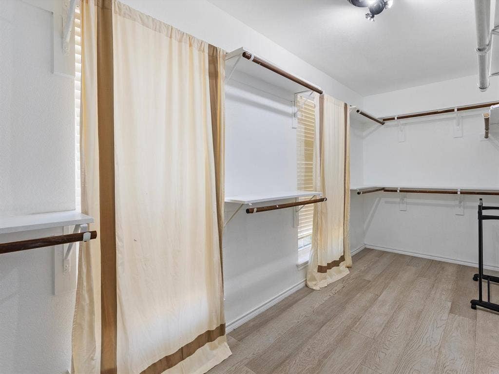 7302 San Carlos Drive, Rowlett, TX 75089 Spacious walk-in closet featuring wood-finish flooring, white walls, built-in shelving, and hanging rods