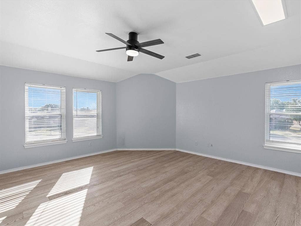 7302 San Carlos Drive, Rowlett, TX 75089 Vaulted ceiling with a contemporary ceiling fan, wood-finish flooring, and multiple windows with blinds