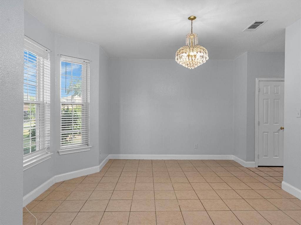 7302 San Carlos Drive, Rowlett, TX 75089 Recessed bay window, tile flooring, contemporary chandelier, paneled interior door, and light-toned walls