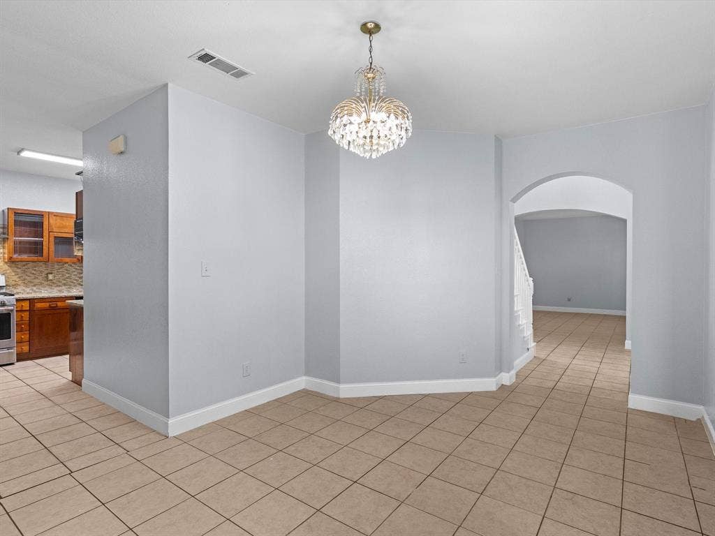7302 San Carlos Drive, Rowlett, TX 75089 Tile flooring with a crystal chandelier, arched doorway, and light-toned walls