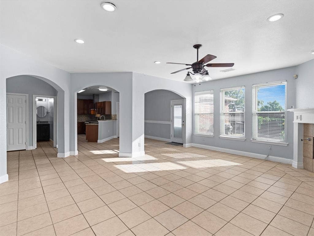 7302 San Carlos Drive, Rowlett, TX 75089 Spacious living area featuring tile flooring, arched doorways, a ceiling fan with integrated lighting, multiple windows, and recessed lighting