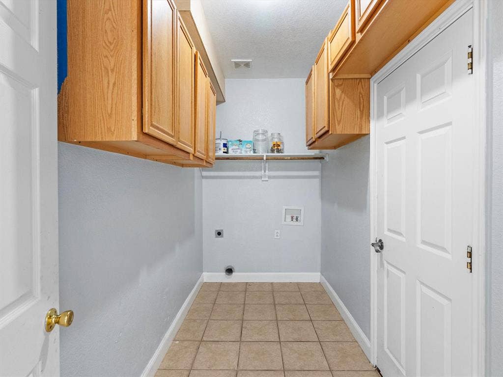 7302 San Carlos Drive, Rowlett, TX 75089 Tiled flooring, upper cabinetry, shelving, and washer/dryer connections