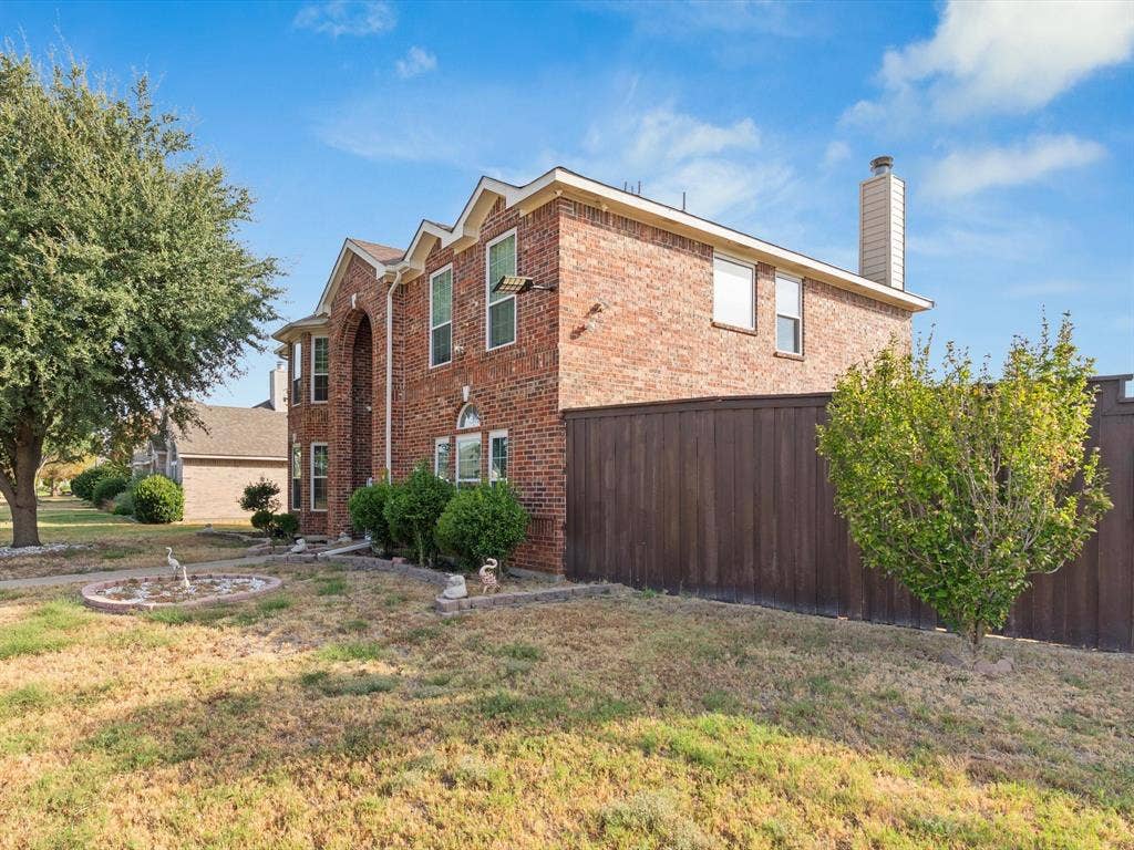 7302 San Carlos Drive, Rowlett, TX 75089 Brick exterior with arched entry, multiple windows, chimney, and privacy fence