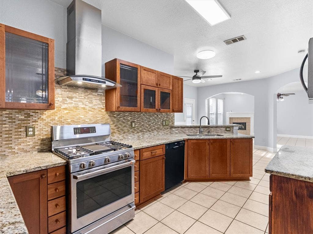 7302 San Carlos Drive, Rowlett, TX 75089 Kitchen featuring stainless steel appliances, wood-finish cabinetry, granite countertops, and a tile backsplash