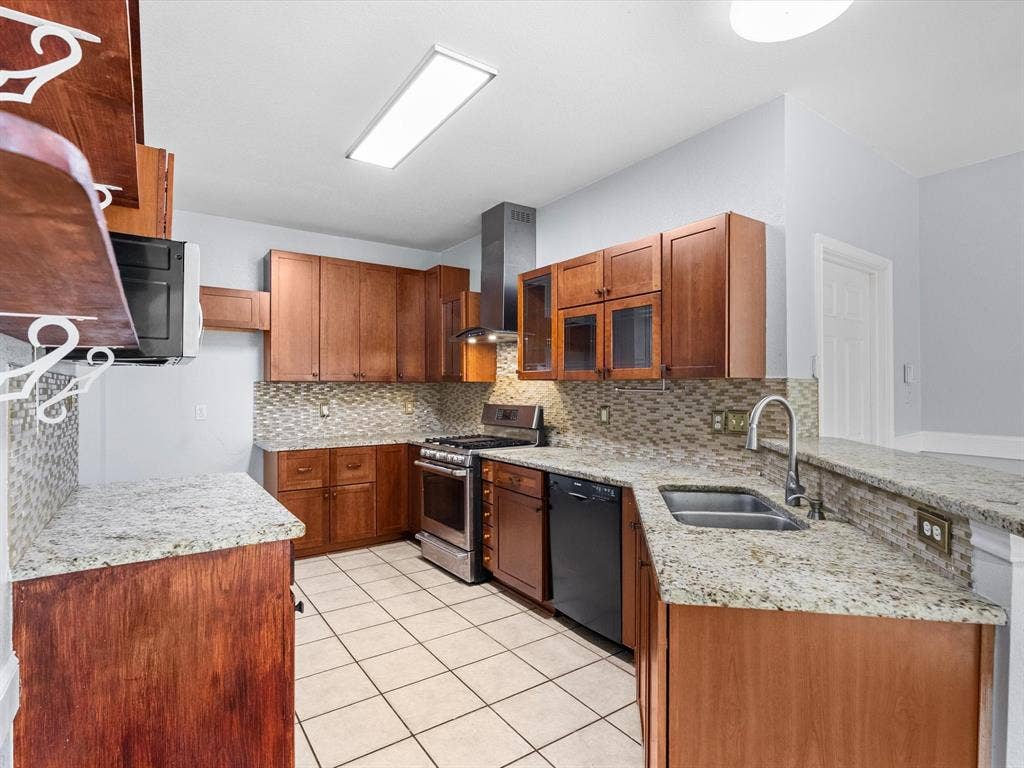 7302 San Carlos Drive, Rowlett, TX 75089 Wood cabinetry, stone-finish countertops, stainless steel appliances, tile flooring, and a mosaic tile backsplash