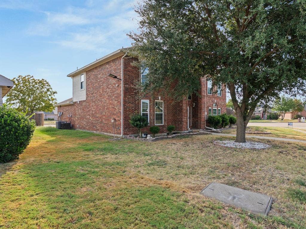 7302 San Carlos Drive, Rowlett, TX 75089 Brick exterior with multiple windows, mature trees, and established shrubbery