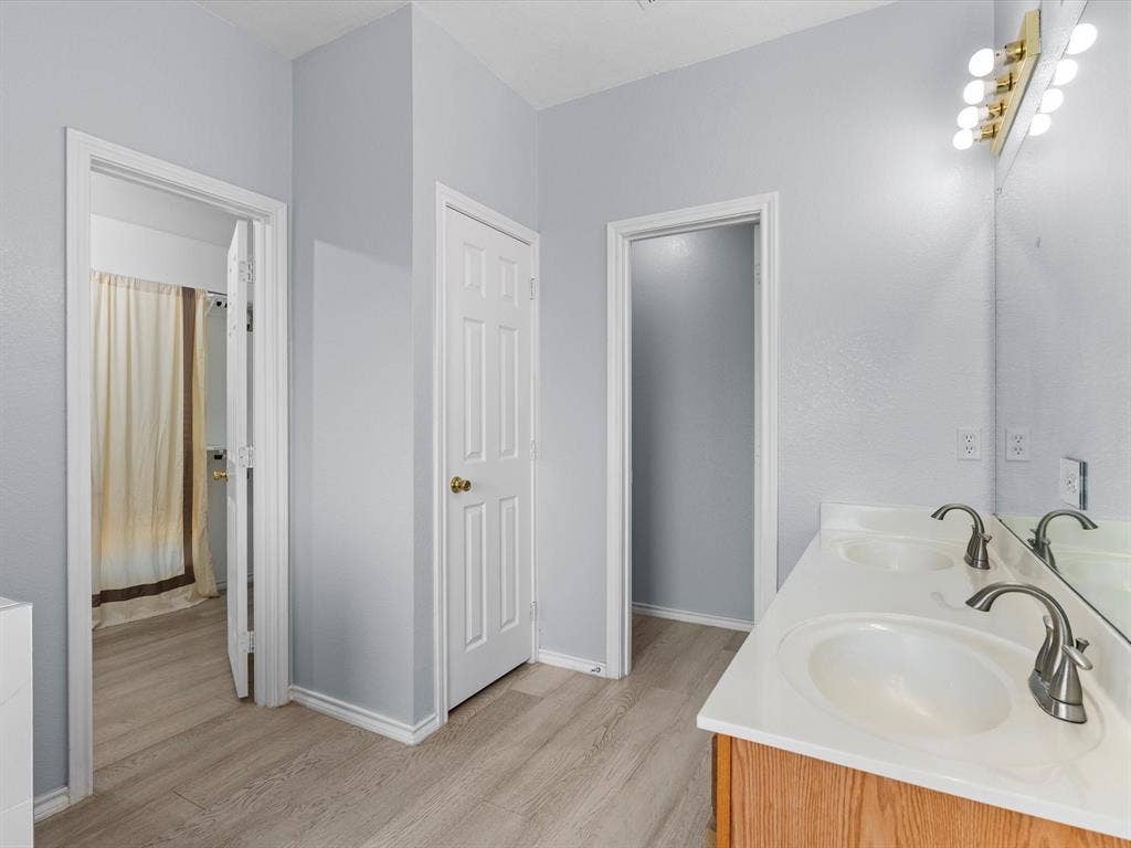 7302 San Carlos Drive, Rowlett, TX 75089 Dual vanity with integrated sinks, brushed nickel faucets, and a light wood-finish cabinet