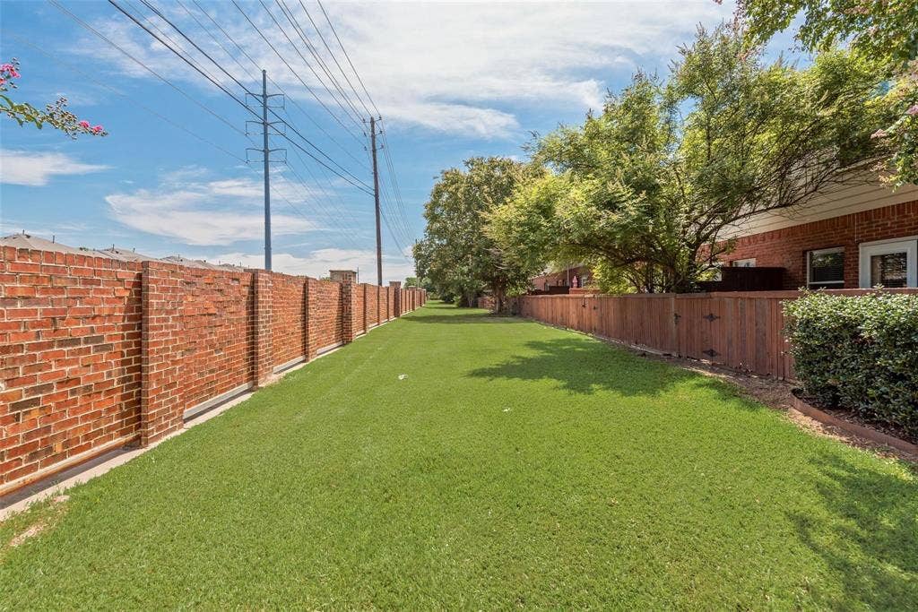 4541 Woodsboro Lane, Plano, TX 75024 Expansive green space featuring a brick privacy wall, wood fence, and mature trees