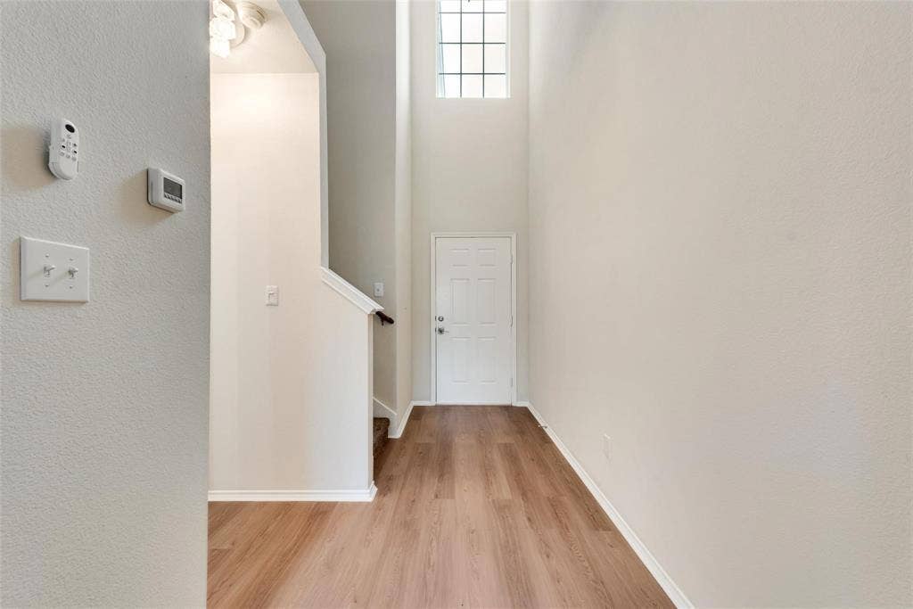 4541 Woodsboro Lane, Plano, TX 75024 Entryway featuring wood-finish flooring, a white paneled door, and a high transom window