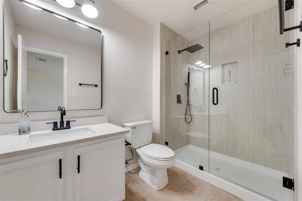 4541 Woodsboro Lane, Plano, TX 75024 White vanity with integrated sink, black fixtures, and a large framed mirror