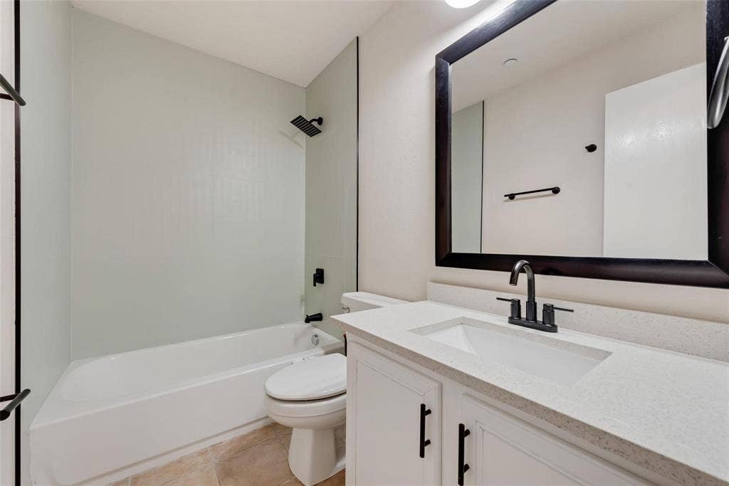 4541 Woodsboro Lane, Plano, TX 75024 Bathroom featuring a white vanity with a light-toned countertop, rectangular undermount sink, and black fixtures
