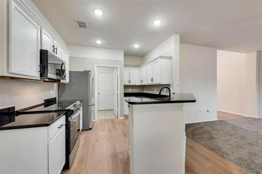 4541 Woodsboro Lane, Plano, TX 75024 Kitchen featuring white cabinetry, dark countertops, stainless steel appliances, wood-finish flooring, and recessed lighting