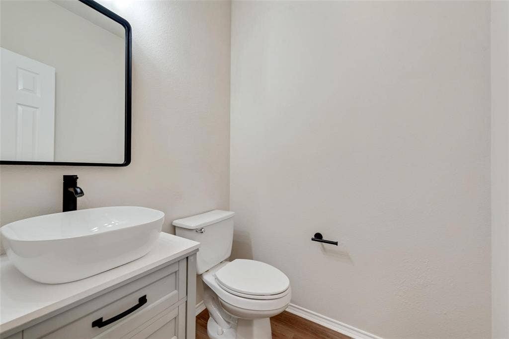4541 Woodsboro Lane, Plano, TX 75024 Contemporary vanity with a vessel sink, dark-finish faucet, and coordinating mirror