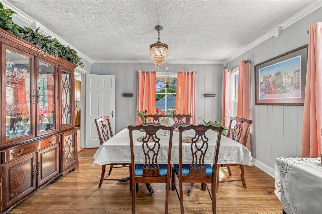 Dining room with decorative chandelier, original hardwood flooring and multiple windows to let in all the natural light.