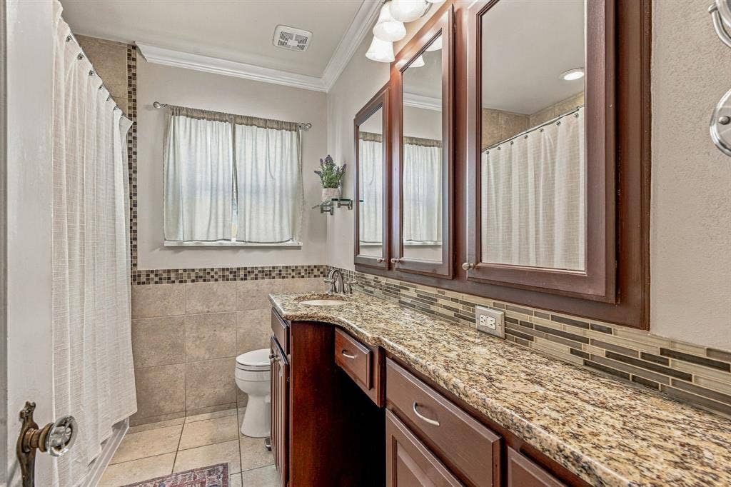 Updated bathroom with granite counters and ample storage.