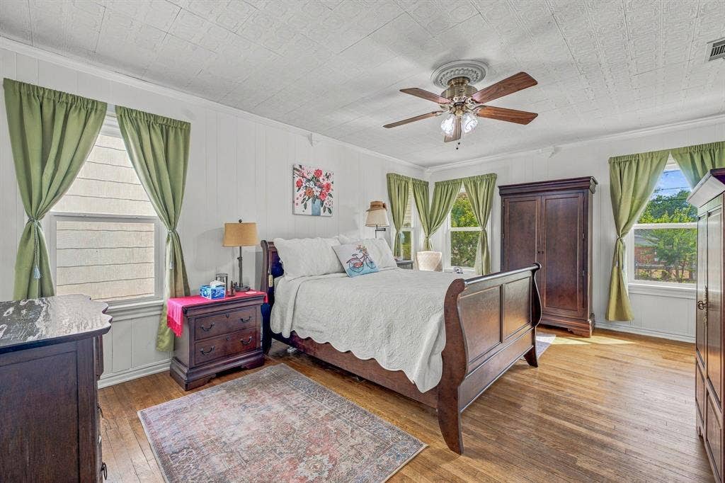 Large primary bedroom with multiple windows to let in ample natural light. Original hardwood flooring and two closets.