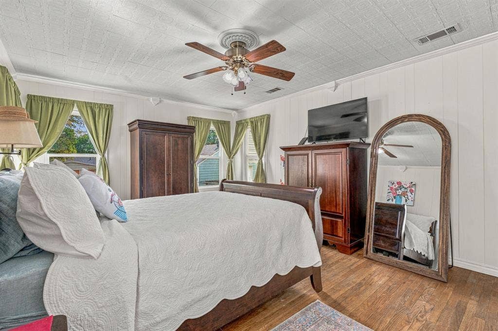 Large primary bedroom with original hardwood floors and two closets.