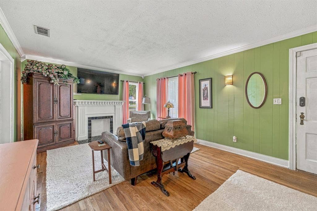 Living room with original hardwood floors and faux fireplace.