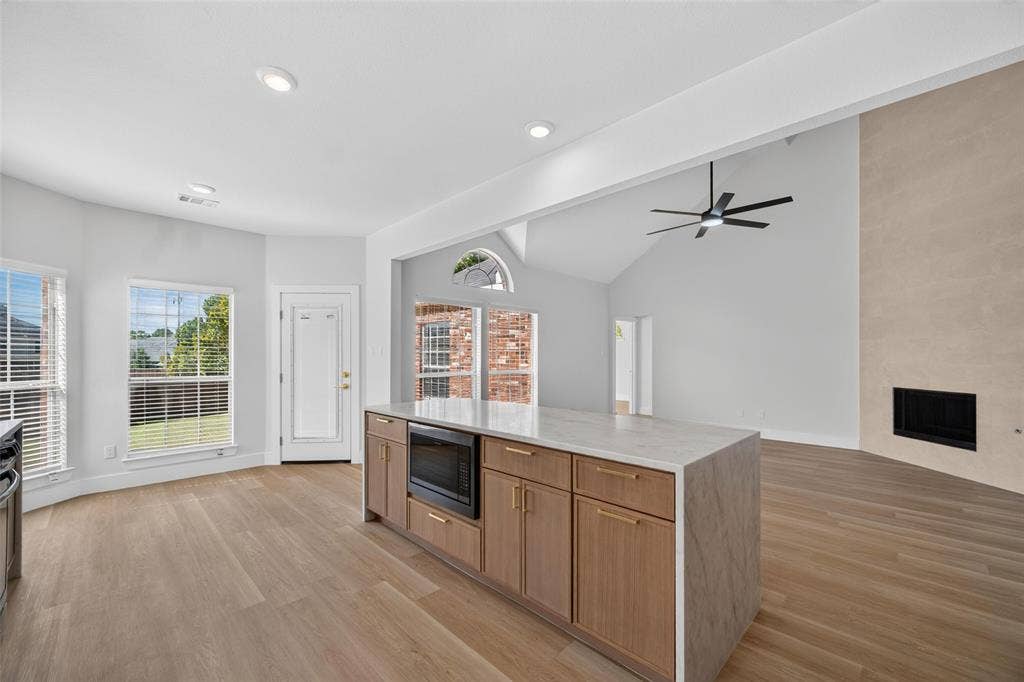 705 N Jordan Road, McKinney, TX 75071 Kitchen island with integrated microwave, light wood-finish cabinetry, and light-colored countertop