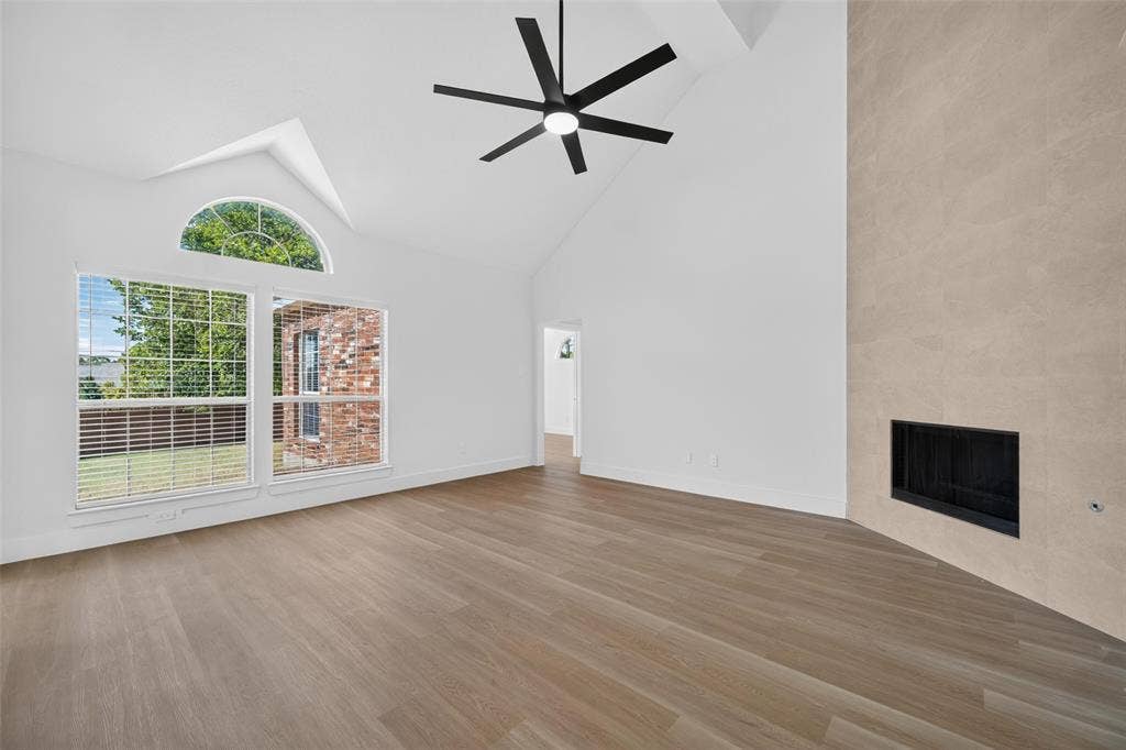 705 N Jordan Road, McKinney, TX 75071 Vaulted ceiling with a contemporary ceiling fan, wood-finish flooring, and a fireplace with a light-toned surround