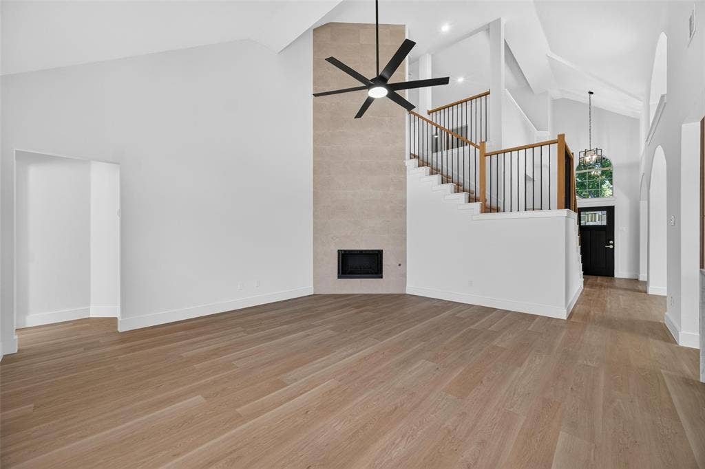 705 N Jordan Road, McKinney, TX 75071 Vaulted ceilings, wood-finish flooring, stone-clad fireplace, open staircase with iron balusters, and a contemporary ceiling fan