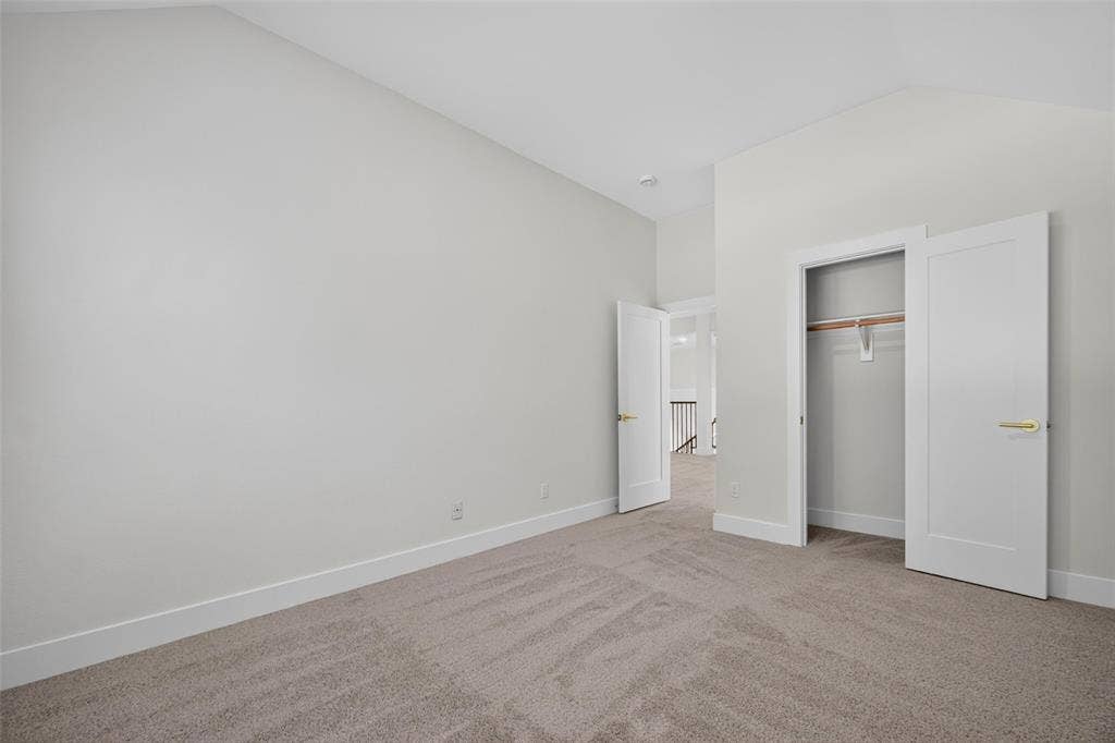 705 N Jordan Road, McKinney, TX 75071 Vaulted ceiling, neutral carpet flooring, a wardrobe with bi-fold doors, and a solid core interior door with gold-tone hardware