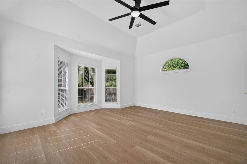 705 N Jordan Road, McKinney, TX 75071 Vaulted ceiling with a black ceiling fan, wood-finish flooring, a bay window with blinds, and an arched window