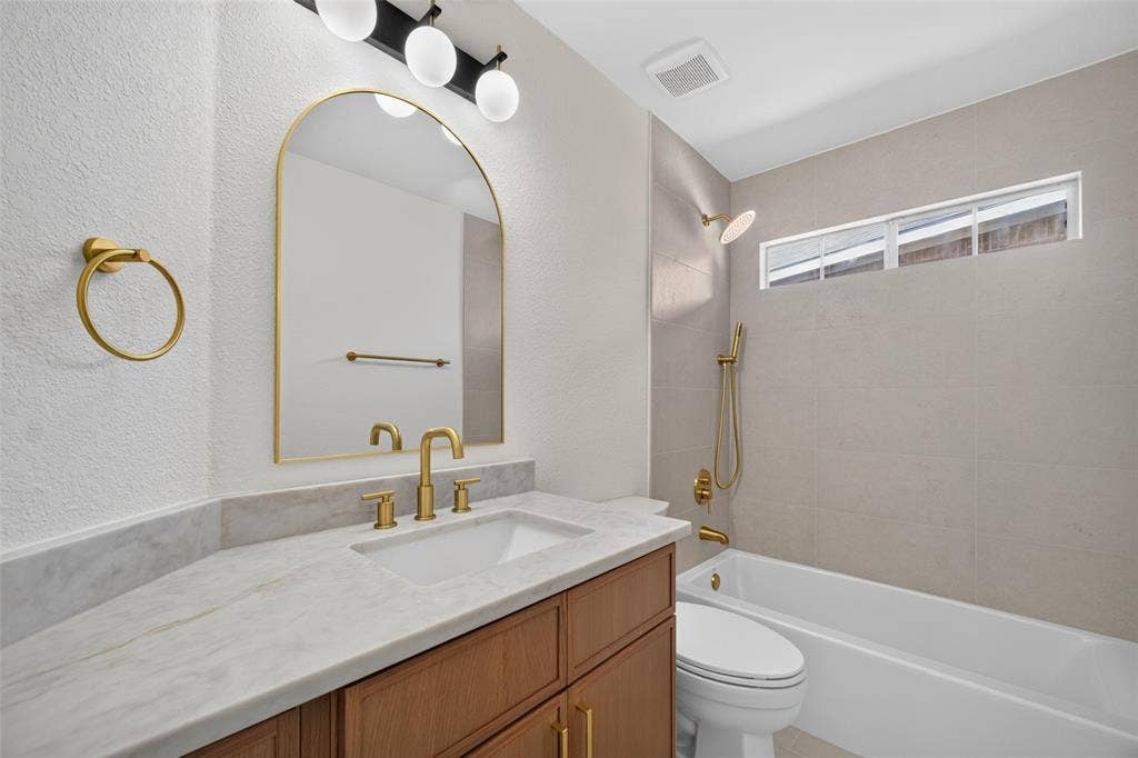 705 N Jordan Road, McKinney, TX 75071 Vanity with rectangular undermount sink, stone countertop, wood-finish cabinetry, and gold-finish fixtures