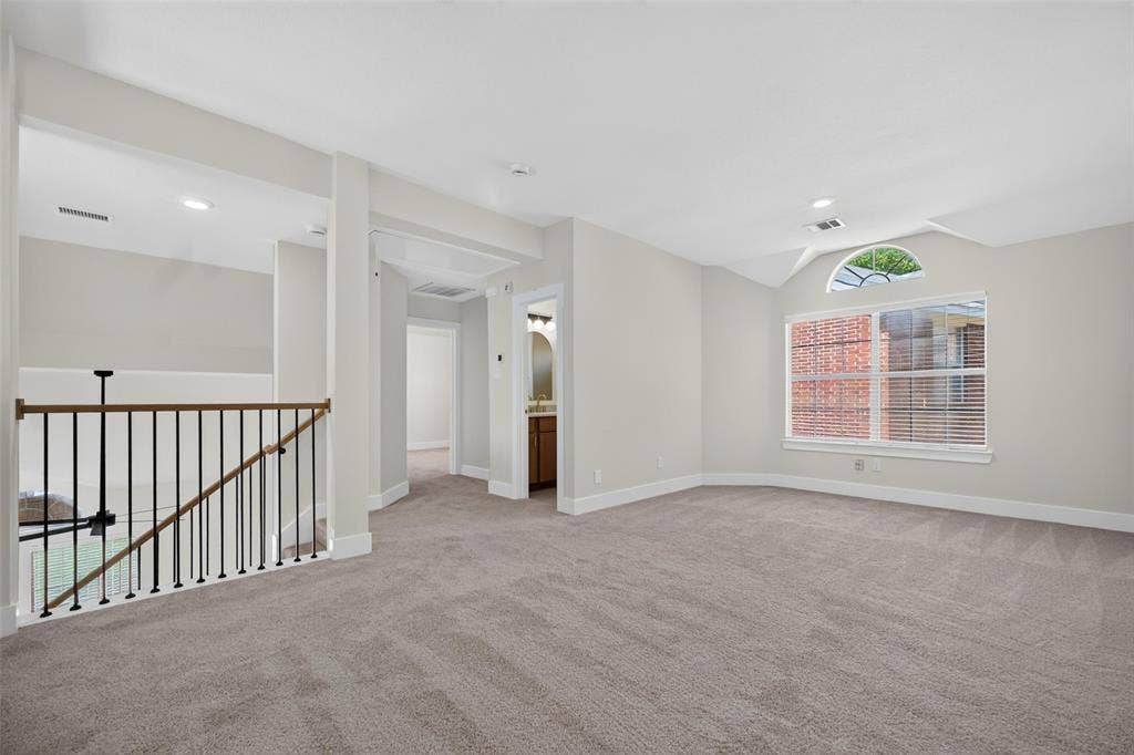 705 N Jordan Road, McKinney, TX 75071 Carpeted loft area featuring a vaulted ceiling with an arched transom window, recessed lighting, and an open stairwell with iron balusters