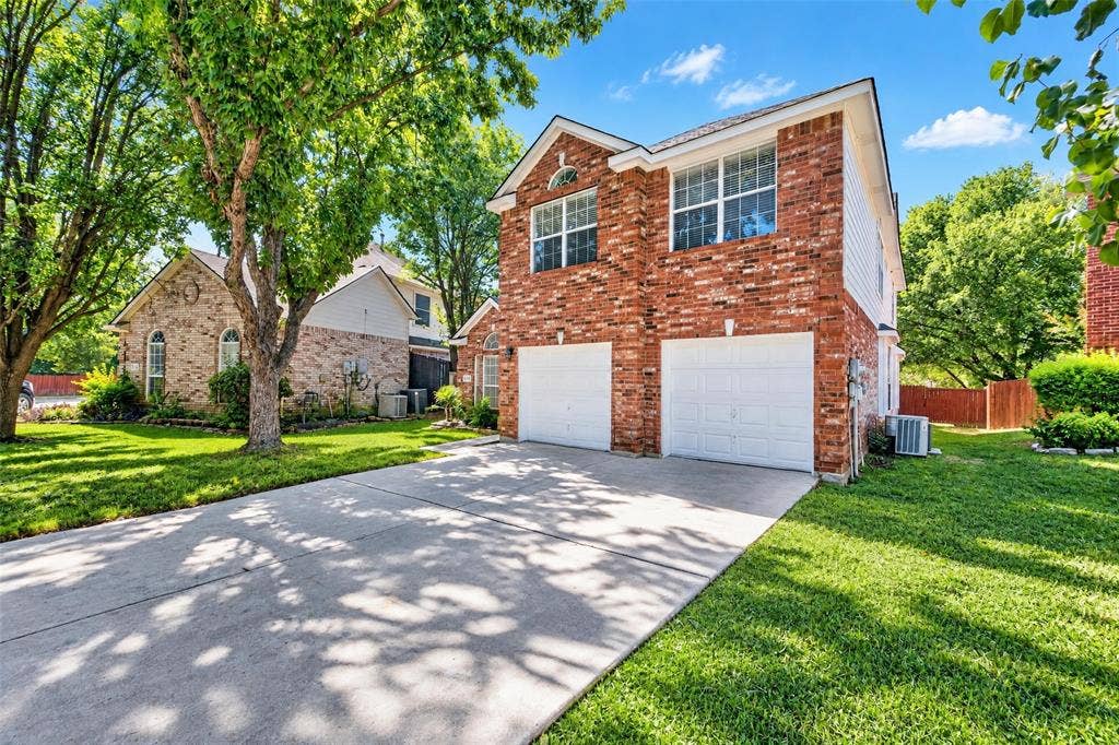 705 N Jordan Road, McKinney, TX 75071 Brick exterior, two-car garage, concrete driveway, established trees, and green lawn