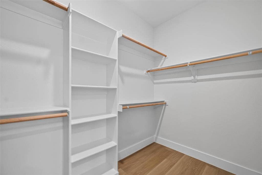 705 N Jordan Road, McKinney, TX 75071 Closet featuring wood-finish flooring, white walls, built-in shelving, and multiple hanging rods
