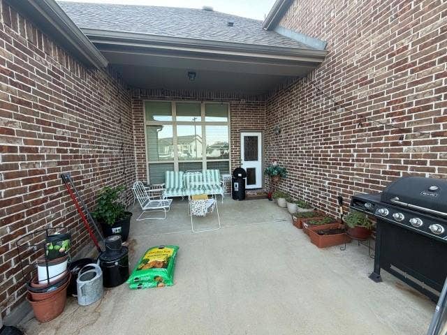 7610 Graystone Drive, Sachse, TX 75048 Brick exterior featuring a covered patio with a concrete surface and a full-light panel door