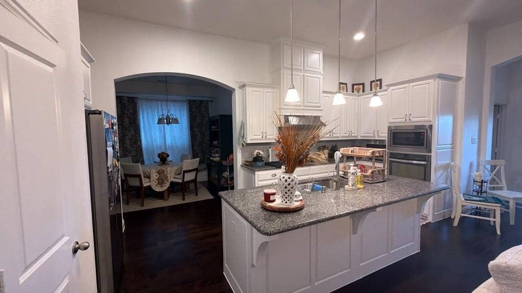 7610 Graystone Drive, Sachse, TX 75048 Kitchen featuring white cabinetry, a large kitchen island with a dark countertop, stainless steel appliances, and pendant lighting