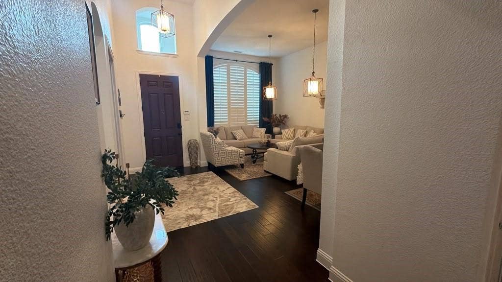 7610 Graystone Drive, Sachse, TX 75048 Arched entryway with a dark wood-finish door, high ceilings, dark wood-finish flooring, and pendant lighting fixtures
