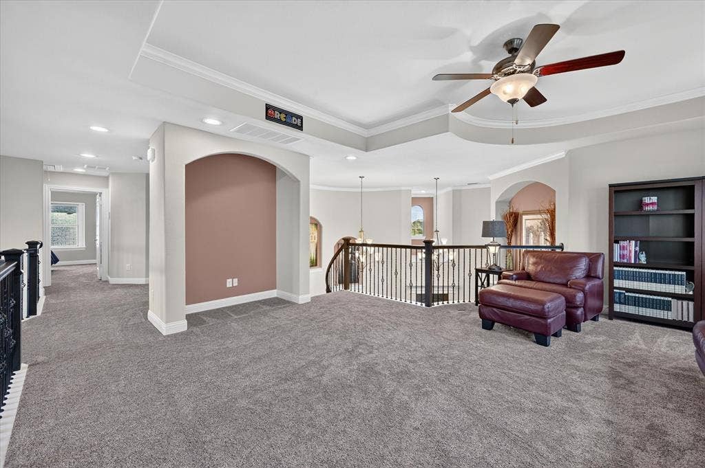 Carpeted loft area featuring a ceiling fan with light, recessed lighting, and an arched niche