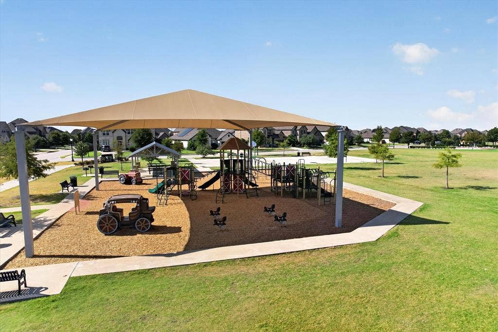 Playground featuring a large shade structure, multiple play structures, and a wood chip surface