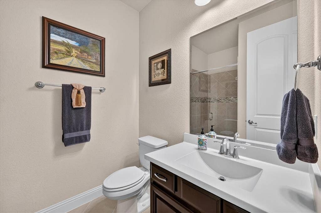Vanity with an integrated sink, polished chrome faucet, wood-finish cabinetry, and a full-width wall mirror