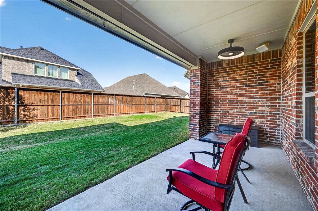 Covered patio with concrete flooring, brick exterior, and a built-in outdoor light fixture